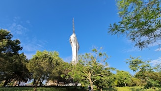 A stunning view of three elegant towers rising against a clear sky, surrounded by lush greenery and wide open spaces.