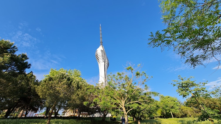 A stunning view of three elegant towers rising against a clear sky, surrounded by lush greenery and wide open spaces.