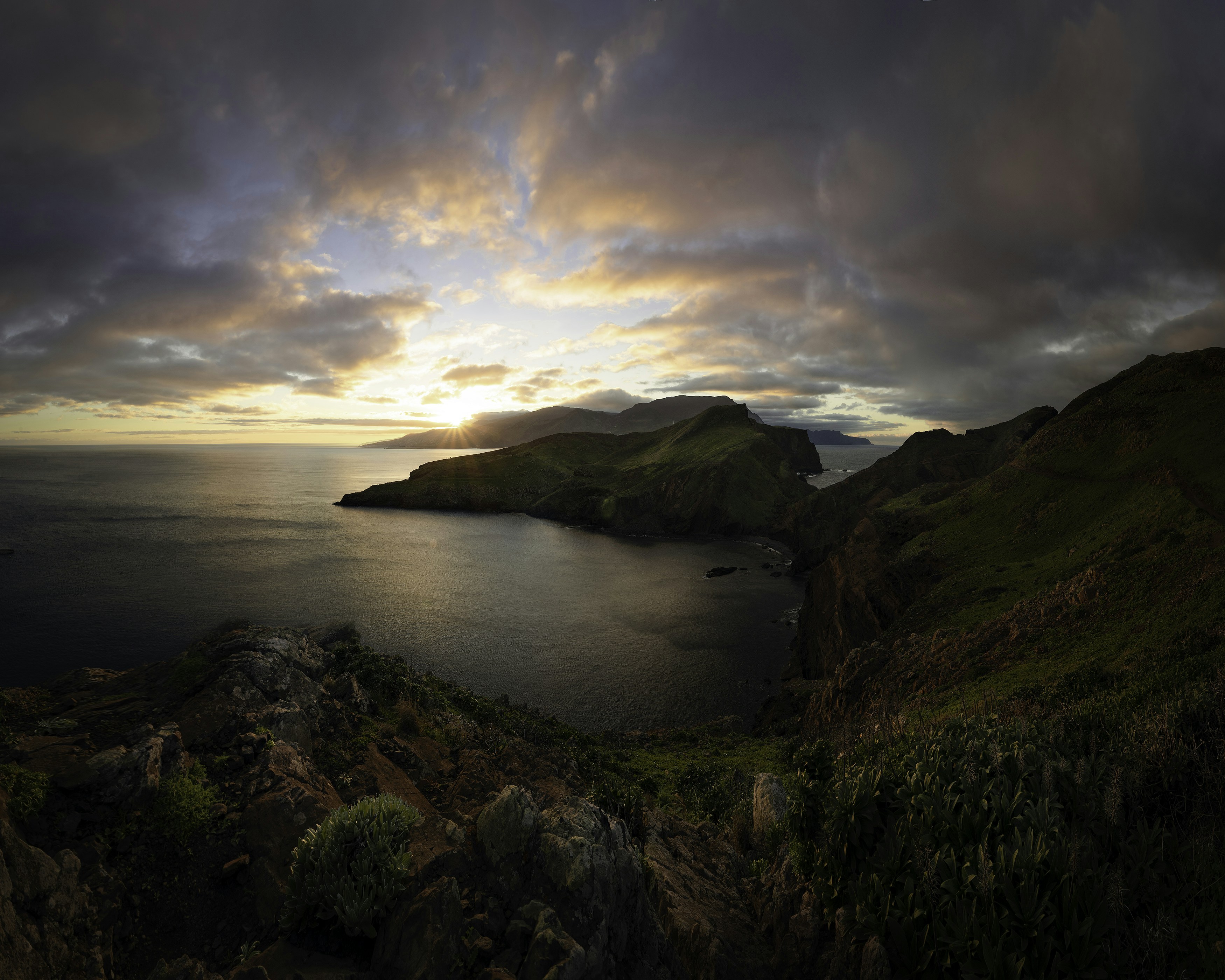 Champ d’herbe verte près d’un plan d’eau sous un ciel nuageux pendant la journée