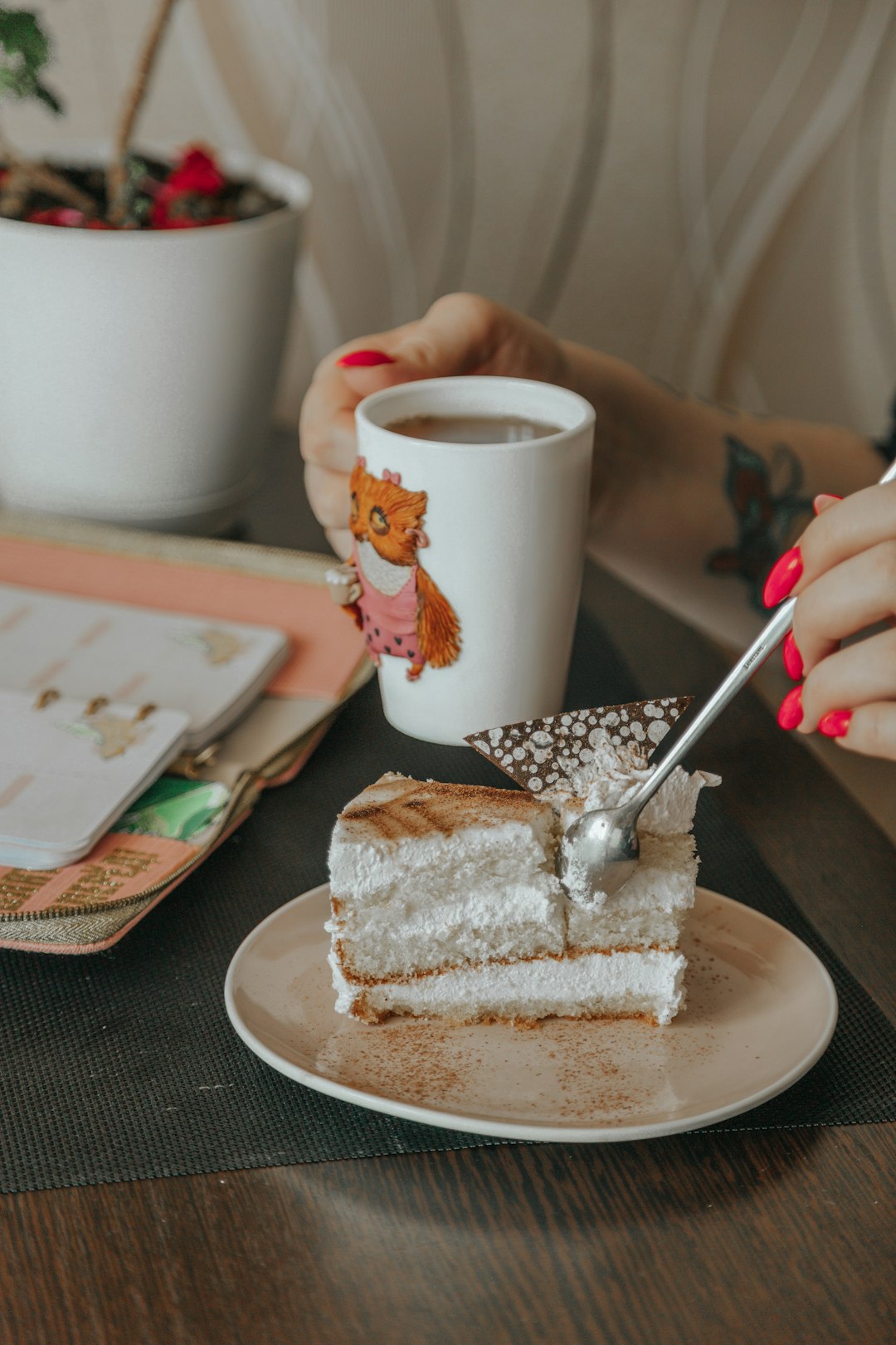 person holding silver spoon and white ceramic mug on white ceramic plate