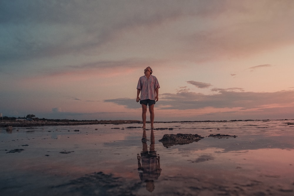 mulher no vestido branco que está na praia durante o pôr do sol