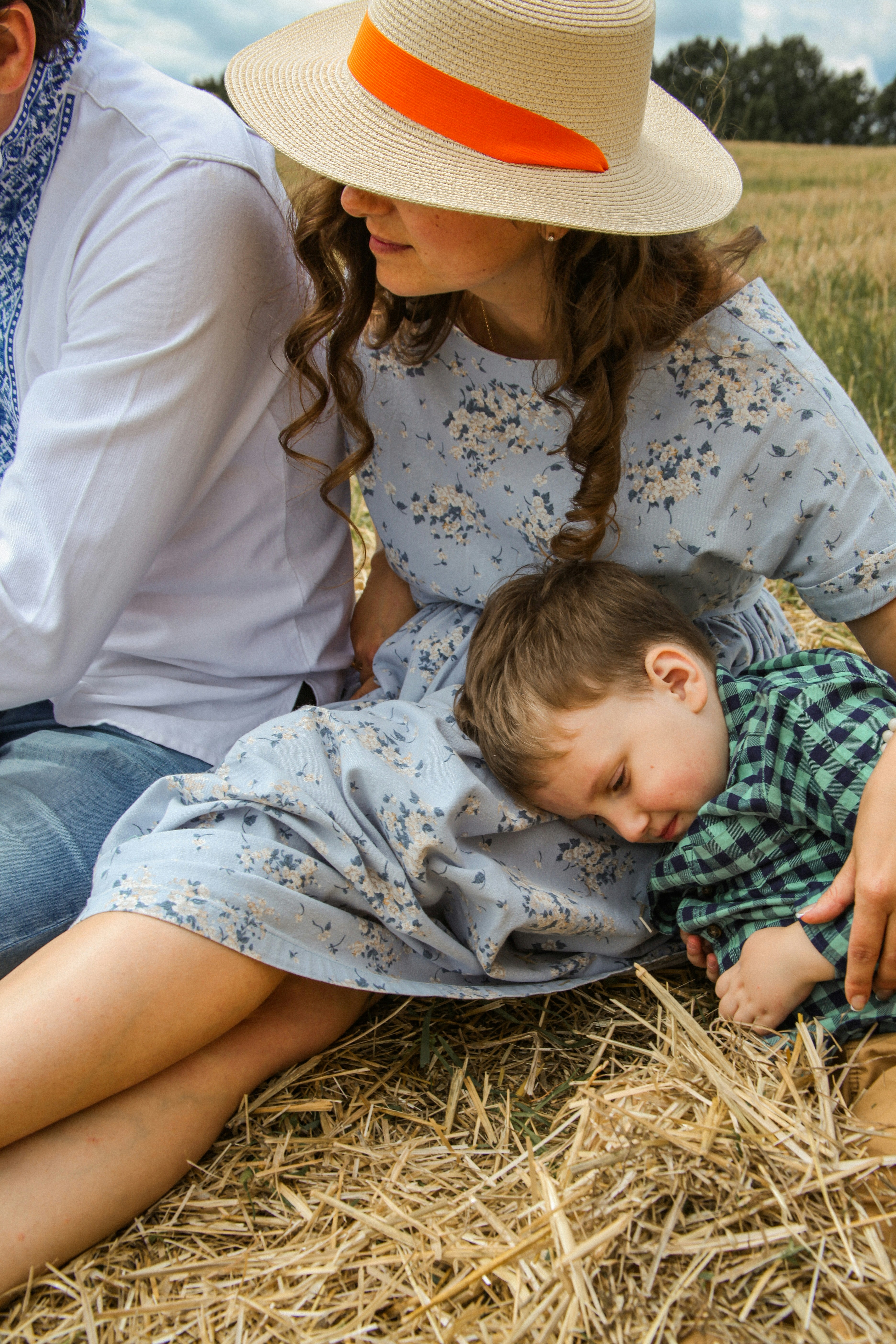 woman in white floral dress carrying baby in white and blue onesie