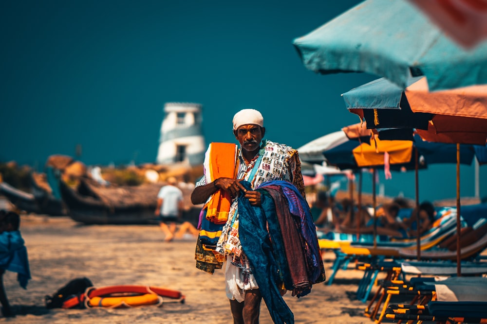 man in white and blue thobe standing on beach during daytime