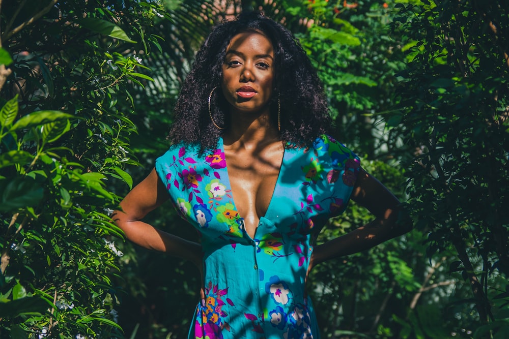 woman in blue and red floral dress standing near green plants