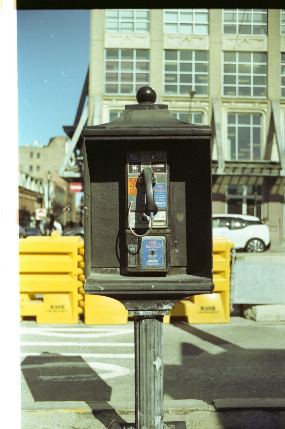 Schwarze Telefonzelle in der Nähe von Yellow Taxi auf der Straße tagsüber