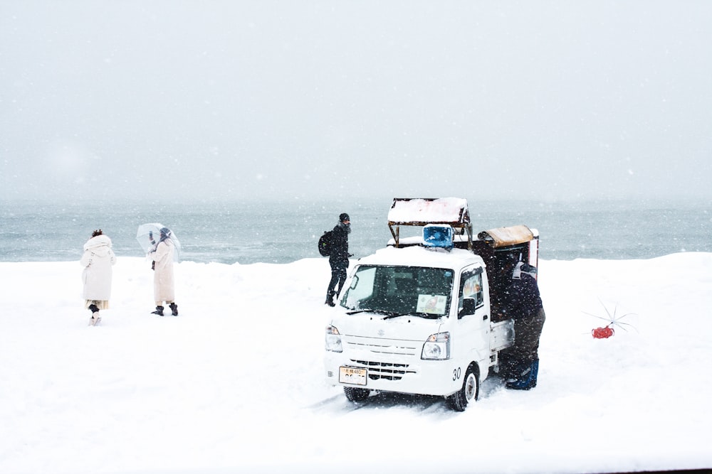 man in black jacket standing beside white van on snow covered ground during daytime