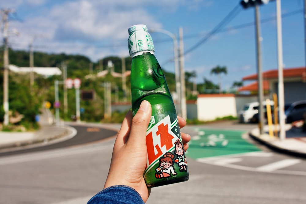 person holding green glass bottle