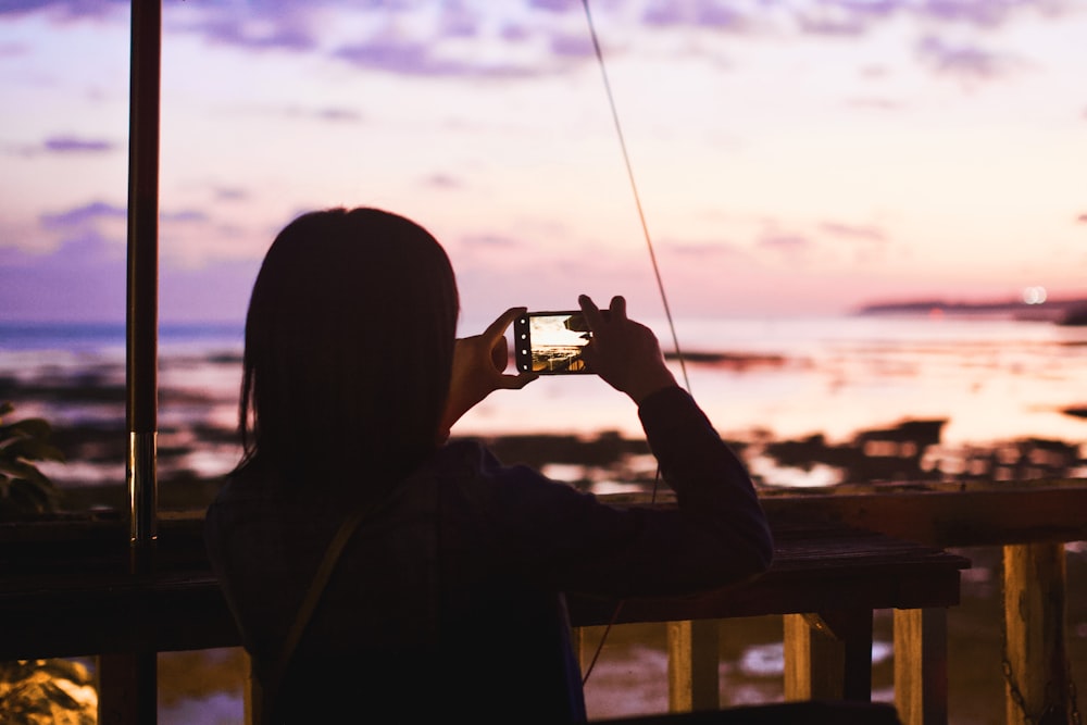 silhouette of man holding camera during sunset