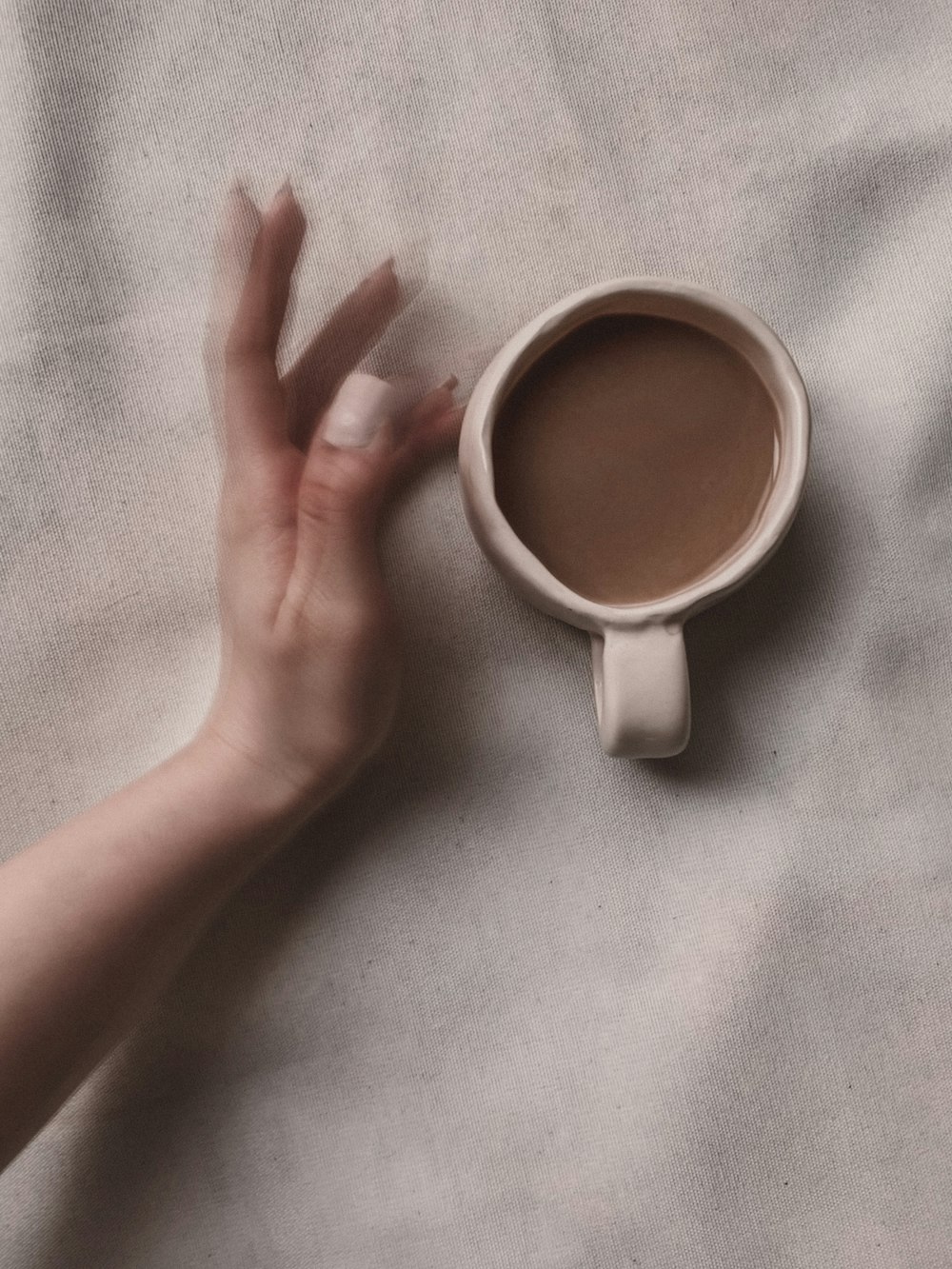 person holding white ceramic mug with brown liquid