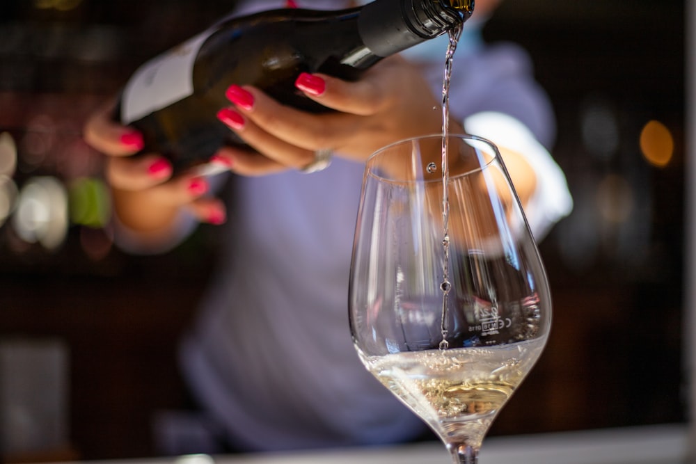 person pouring wine on wine glass