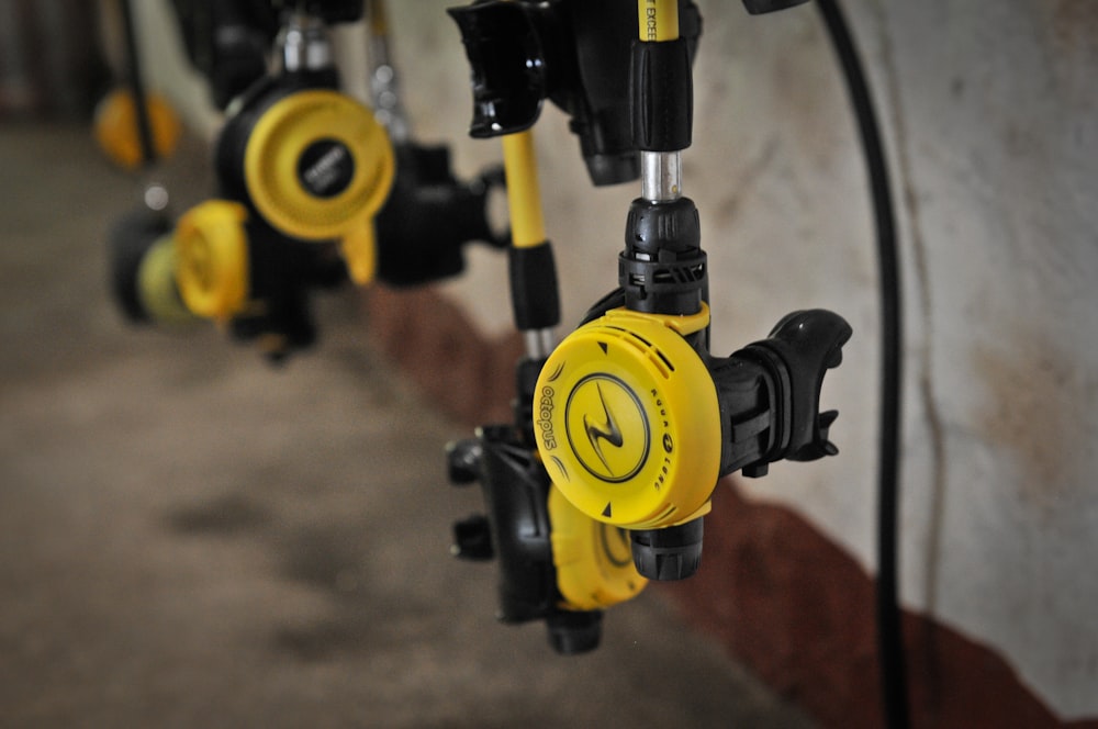 a row of yellow and black fire hydrants next to a wall