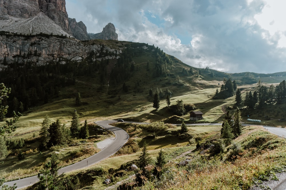 green grass field near mountain under white clouds during daytime