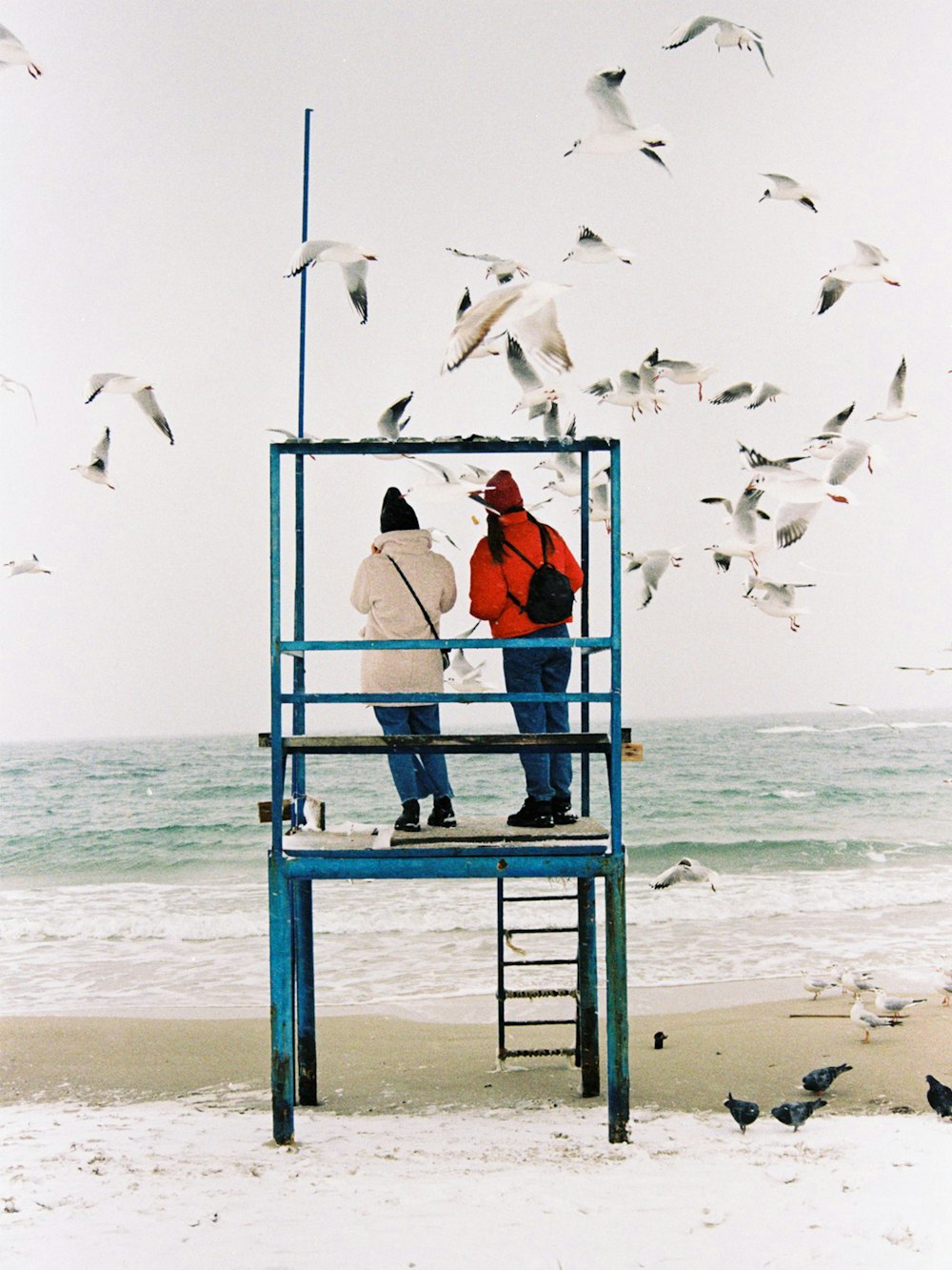 woman in orange tank top sitting on blue metal ladder near sea during daytime