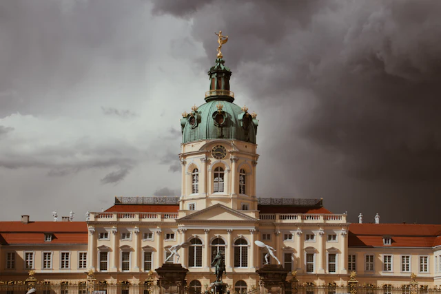Charlottenburg Palace's green baroque dome, topped with a gilded figure, stands against a dramatic stormy sky.