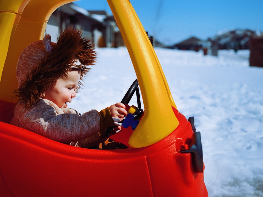 child in red and yellow plastic slide