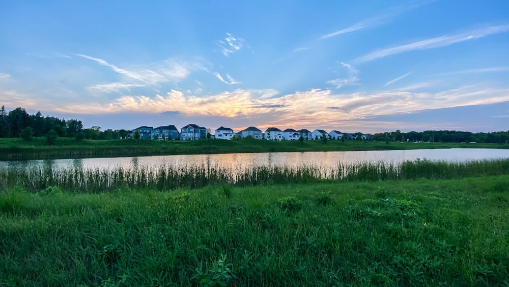 green grass field near lake under blue sky during daytime