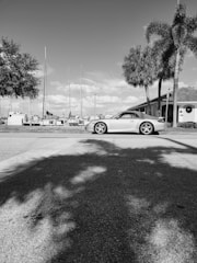A sleek car parked on a sunlit Miami Beach street near palm trees