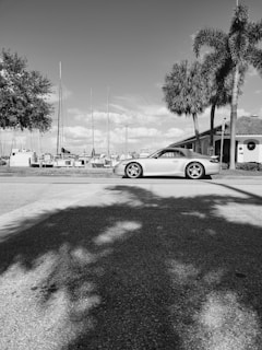 A sleek luxury car parked along the sunny Cannes waterfront with yachts in the background