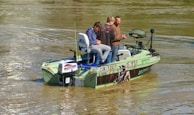 A group of friends in Fish Gear Apparel sharing a laugh while prepping their boat for a day on the river.
