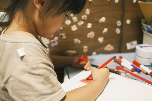 A teen engrossed in an intricate activity book with pencils and markers.