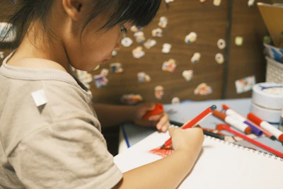 A child carefully adding details to a colorful drawing with a big smile.