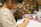 A focused boy sketching in a bright art studio filled with colorful drawings on the walls.
