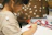 A focused boy sketching in a bright art studio filled with colorful drawings on the walls.