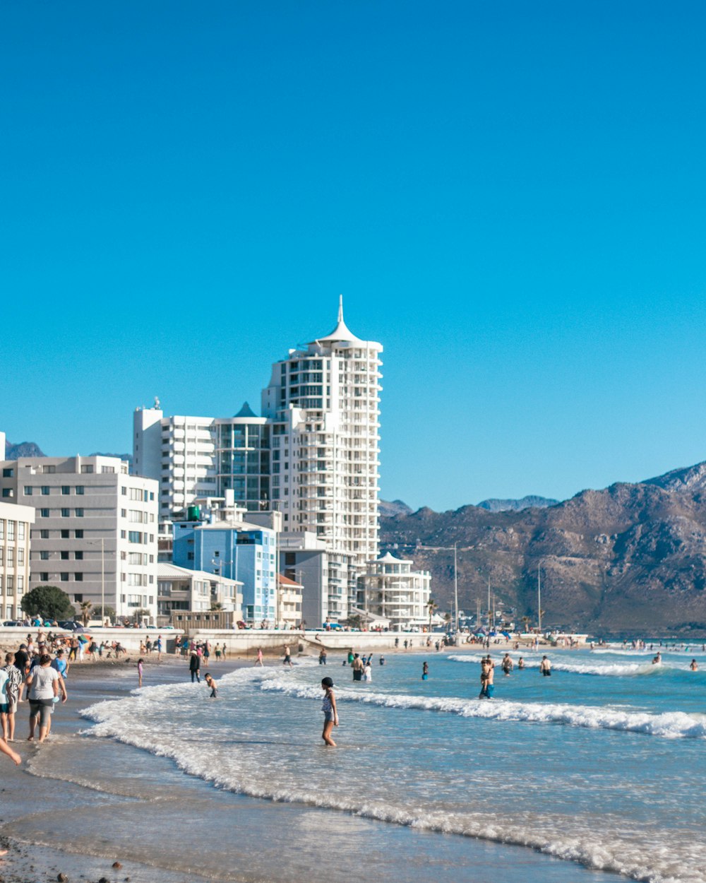 people on beach near city buildings during daytime