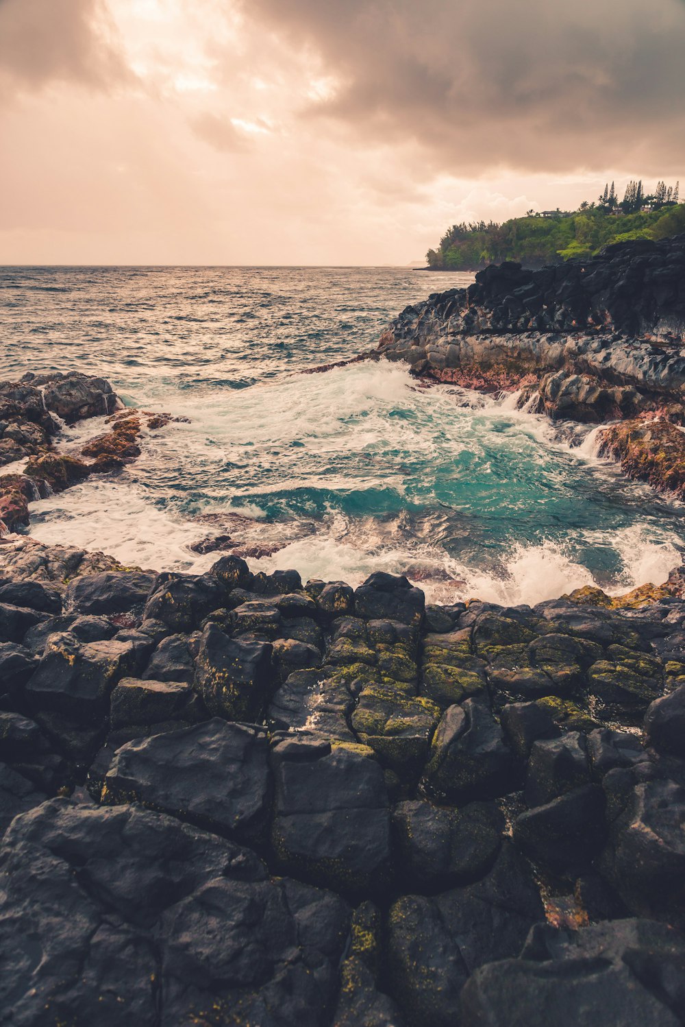 rocky shore with ocean waves crashing on rocks during daytime