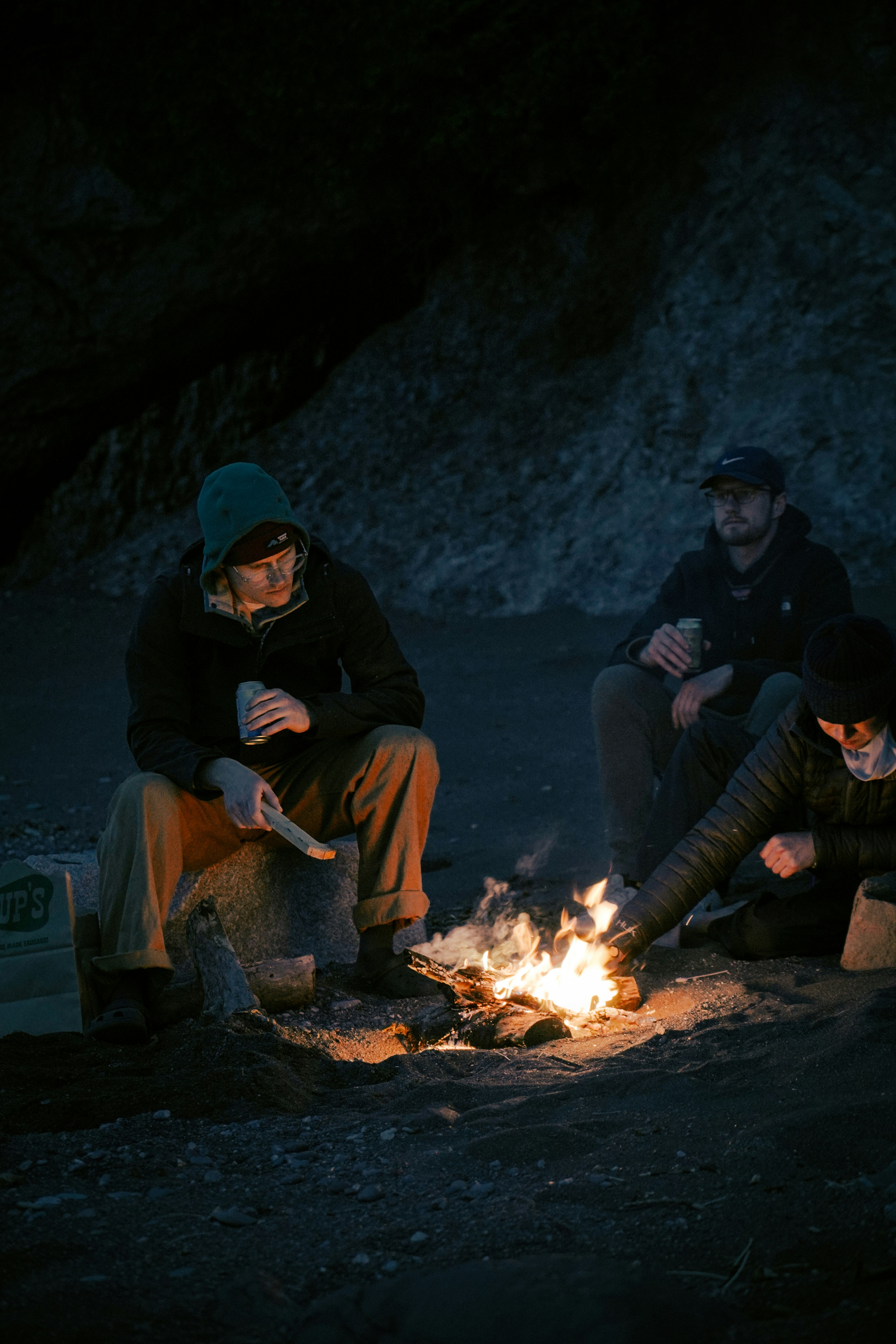 man and woman sitting on brown log near bonfire during daytime