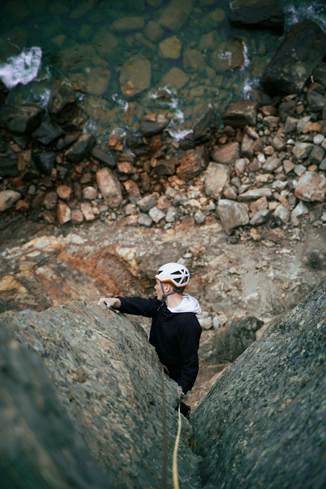 man in black jacket and white cap standing on rocky ground