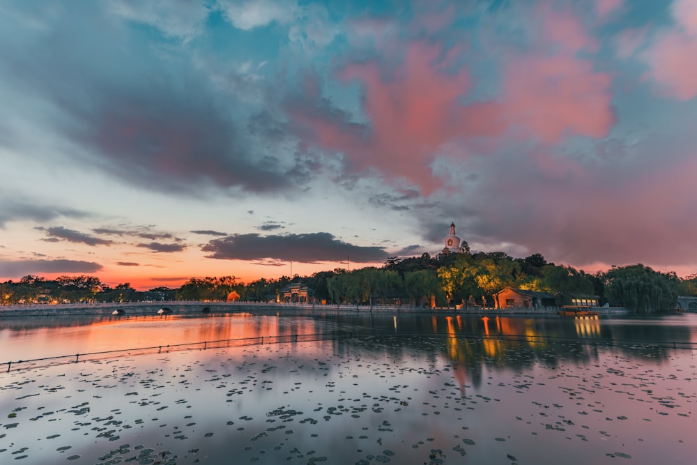 specchio d'acqua vicino agli alberi sotto il cielo nuvoloso durante il giorno