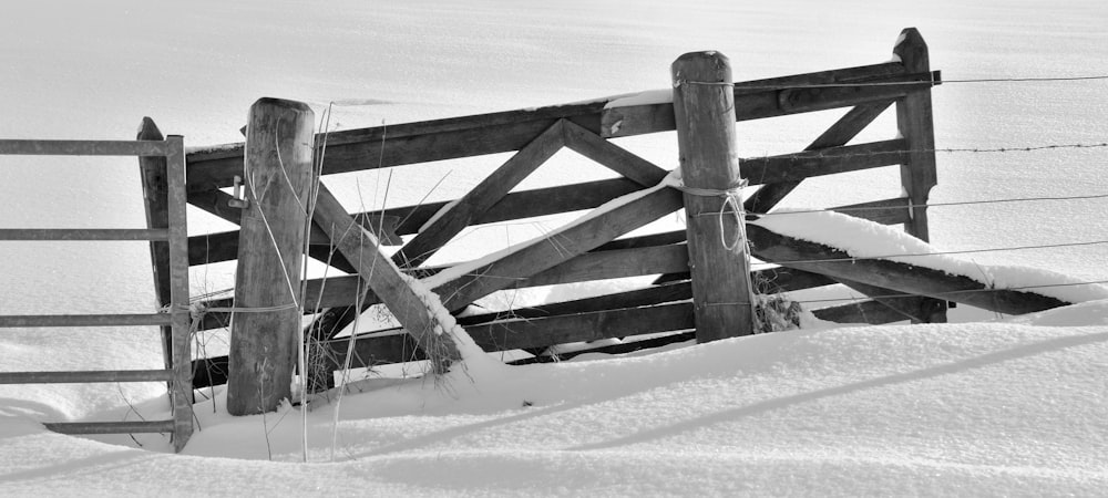 grayscale photo of wooden fence on snow field