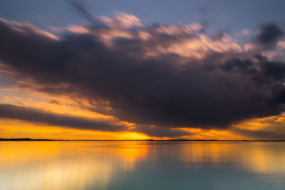 body of water under cloudy sky during sunset