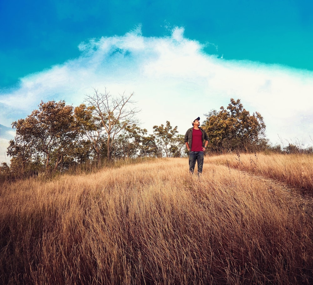 man in red jacket standing on brown grass field during daytime