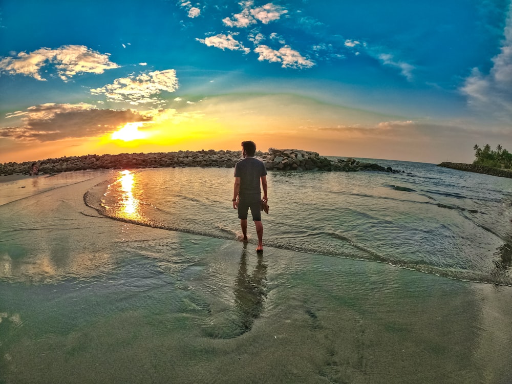 man and woman walking on beach during sunset