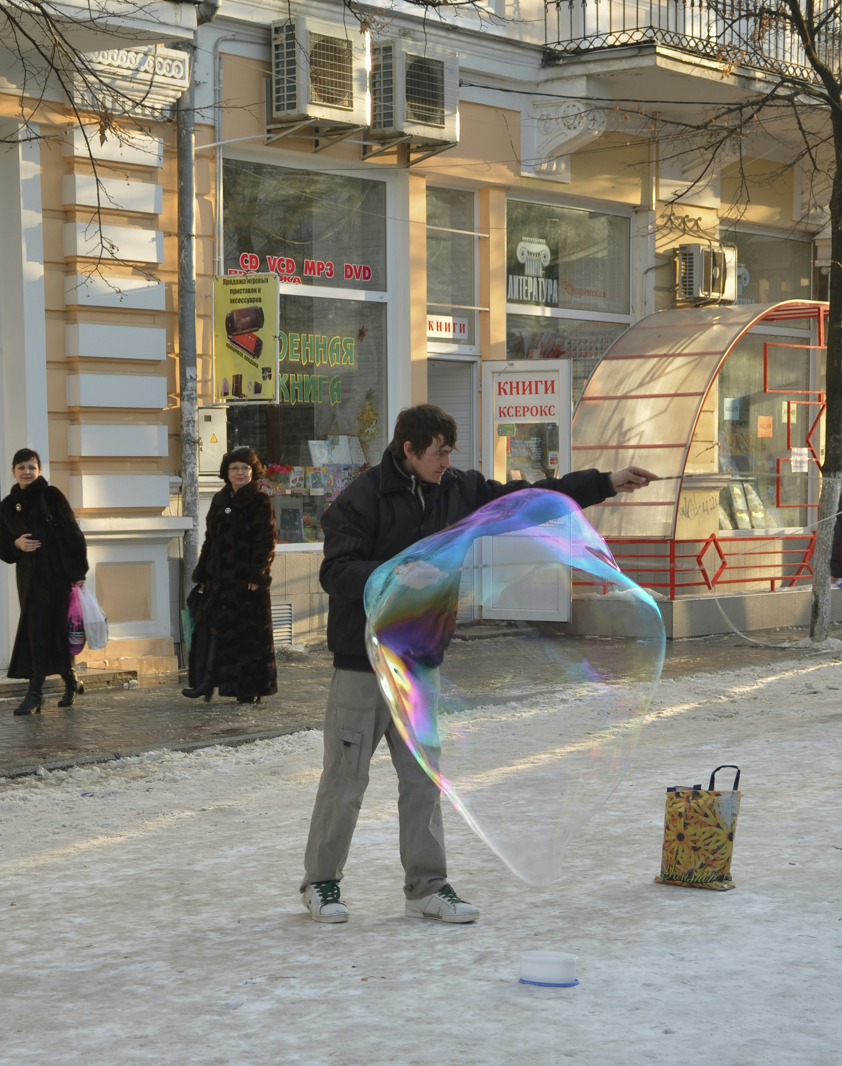 man in black jacket and pants standing in front of clear glass building during daytime