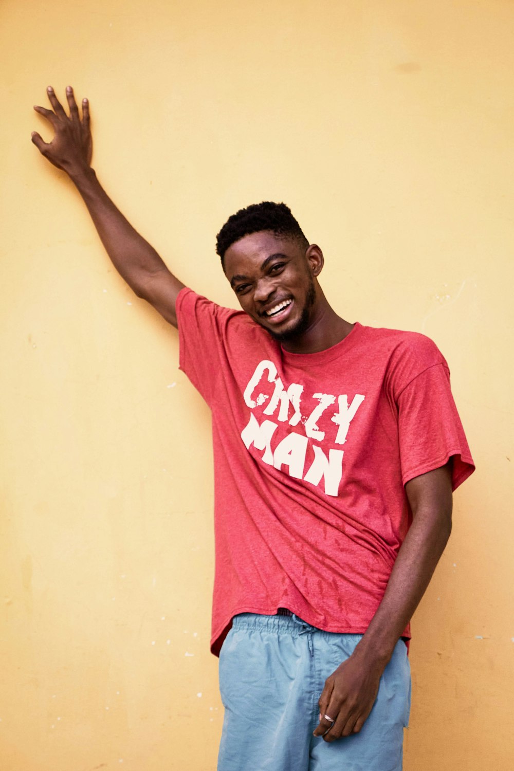 man in red crew neck t-shirt and blue denim jeans