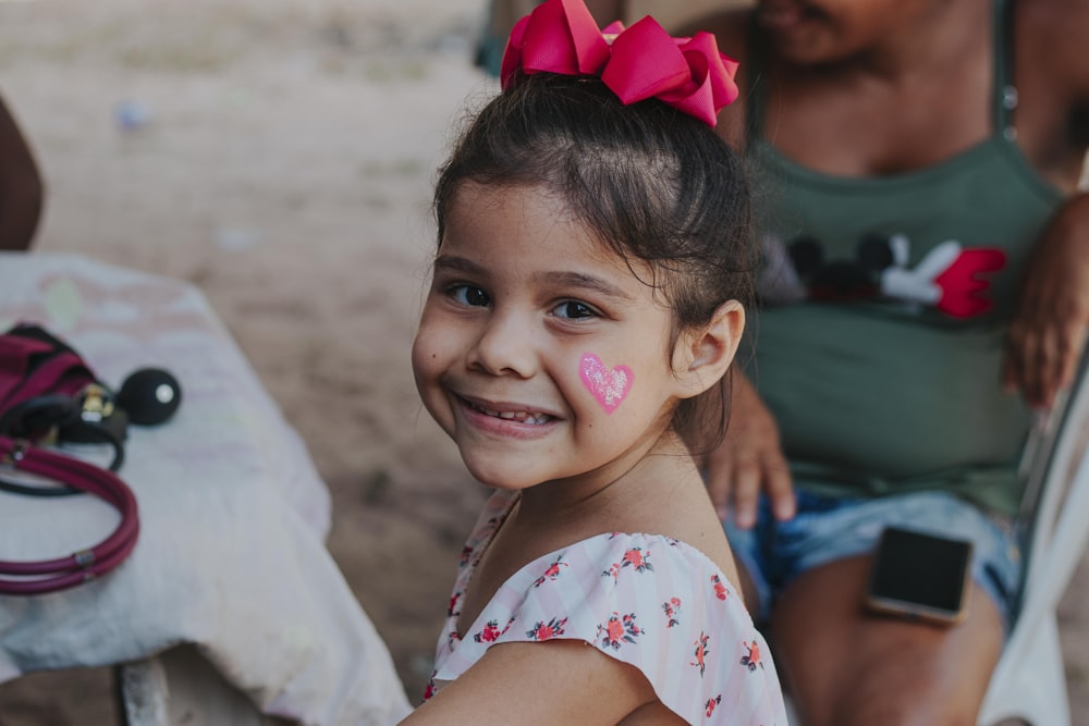 a little girl with a heart painted on her cheek