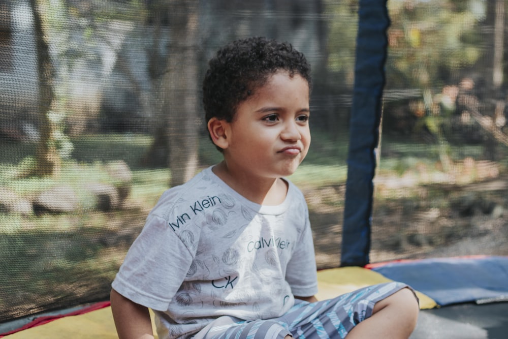 a young boy sitting on top of a trampoline