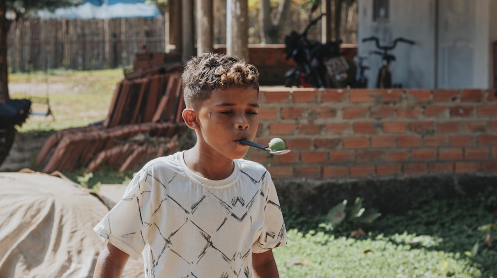 boy in white crew neck t-shirt holding green lollipop