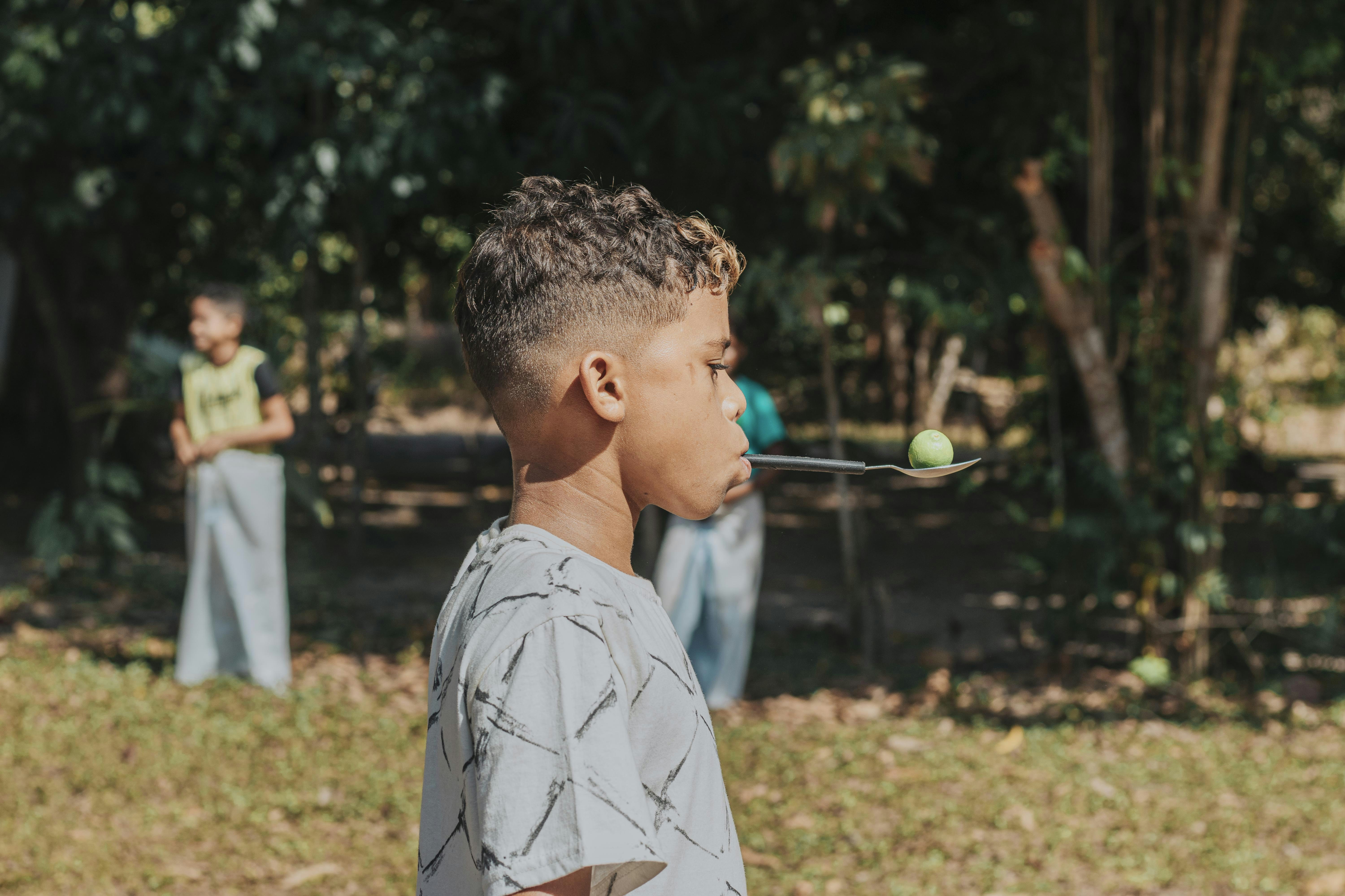 boy in white and black floral shirt standing on green grass field during daytime