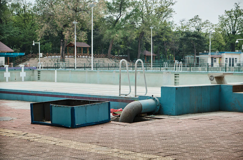 Empty pool with stained waterline tile and equipment pulled for service