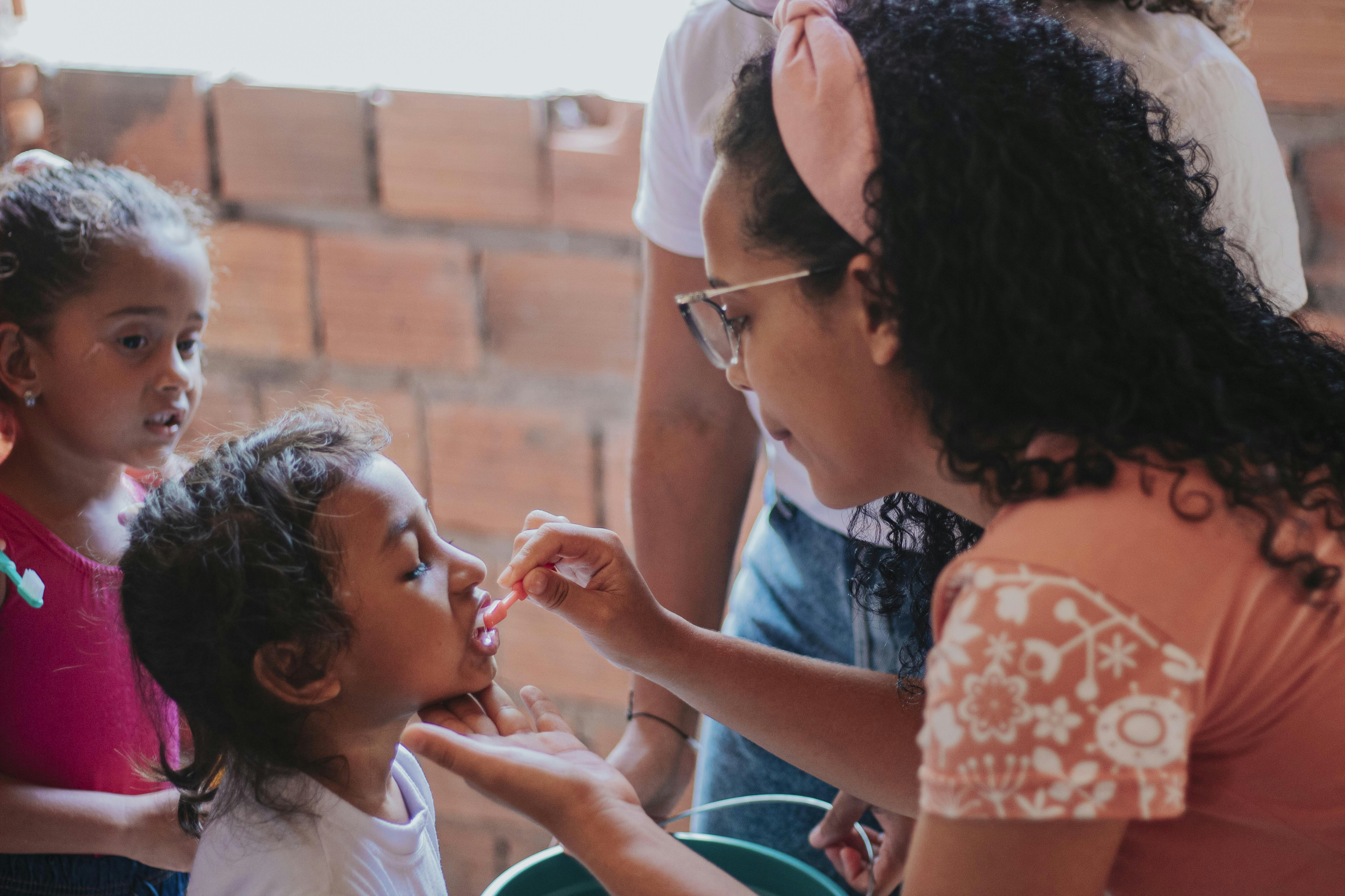 mulher na camisa branca que segura a menina na camisa floral branca e cor-de-rosa
