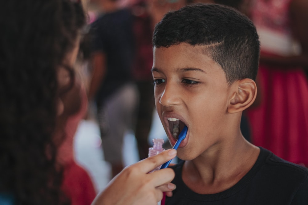 boy in black tank top holding blue plastic toy