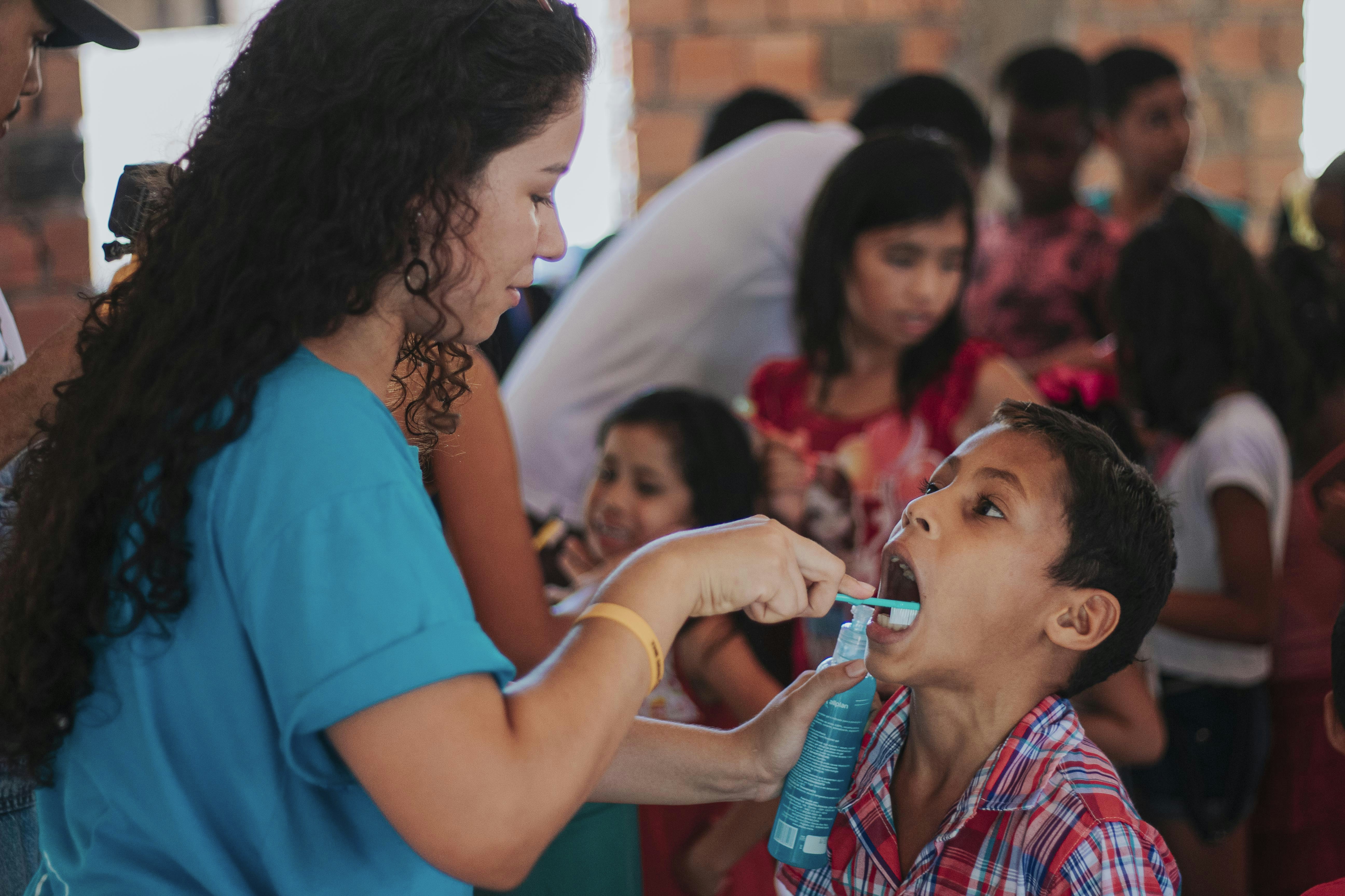 mulher na camisa azul que transporta a criança na camisa xadrez vermelha e branca