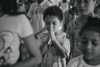 Children gathered in a circle holding hands during a prayer session.