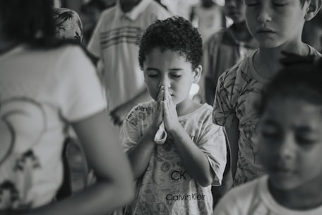 Teachers and students praying together in a bright school chapel.