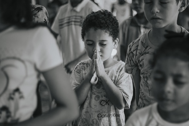 Children gathered around a catechism teacher, holding prayer books with warm church light.