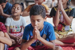 Smiling kids engaged in a mindful breathing exercise on soft mats inside the daycare.